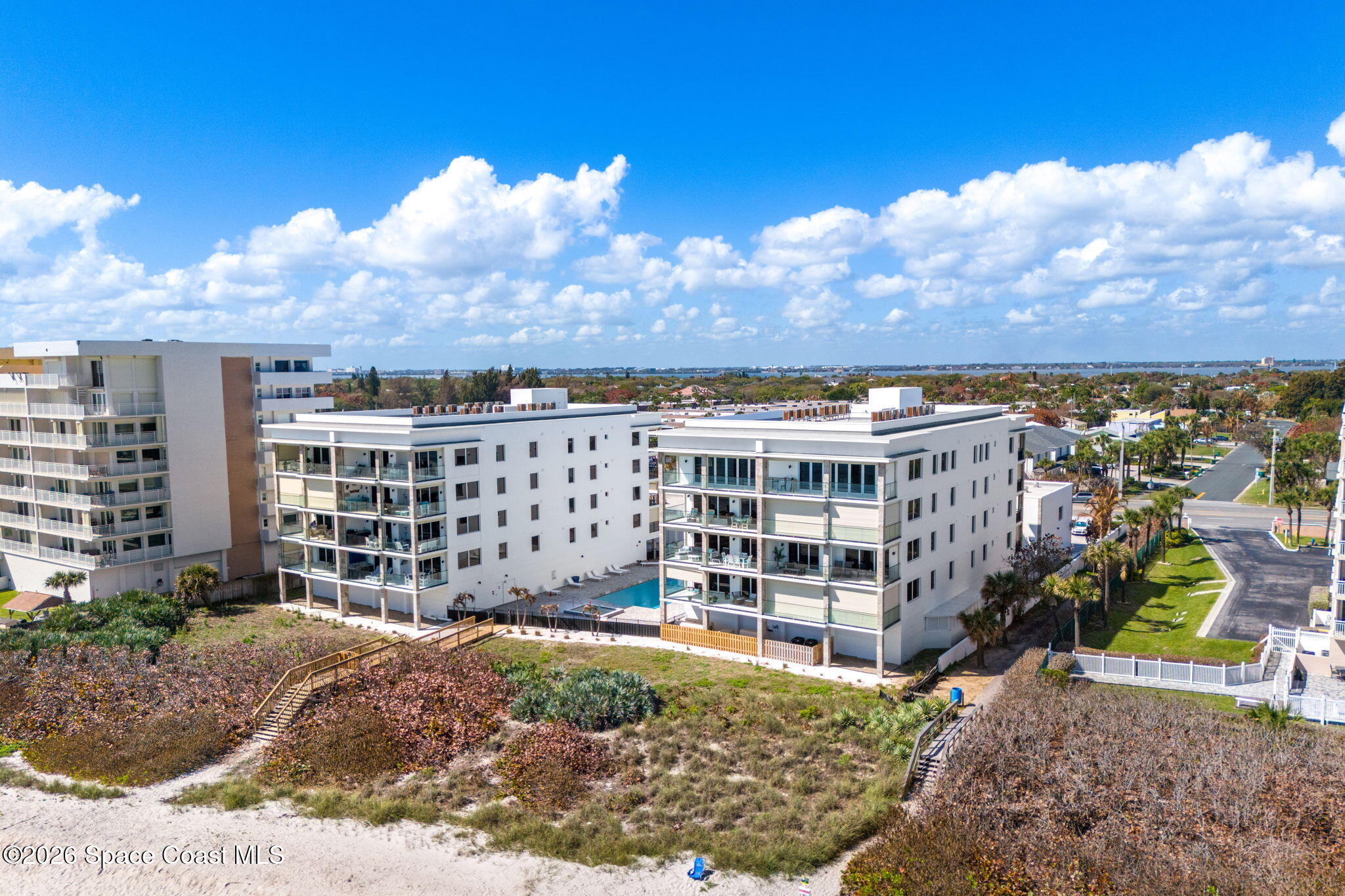 Exterior of the modern white 2795 Ocean condominium building framed by palms
