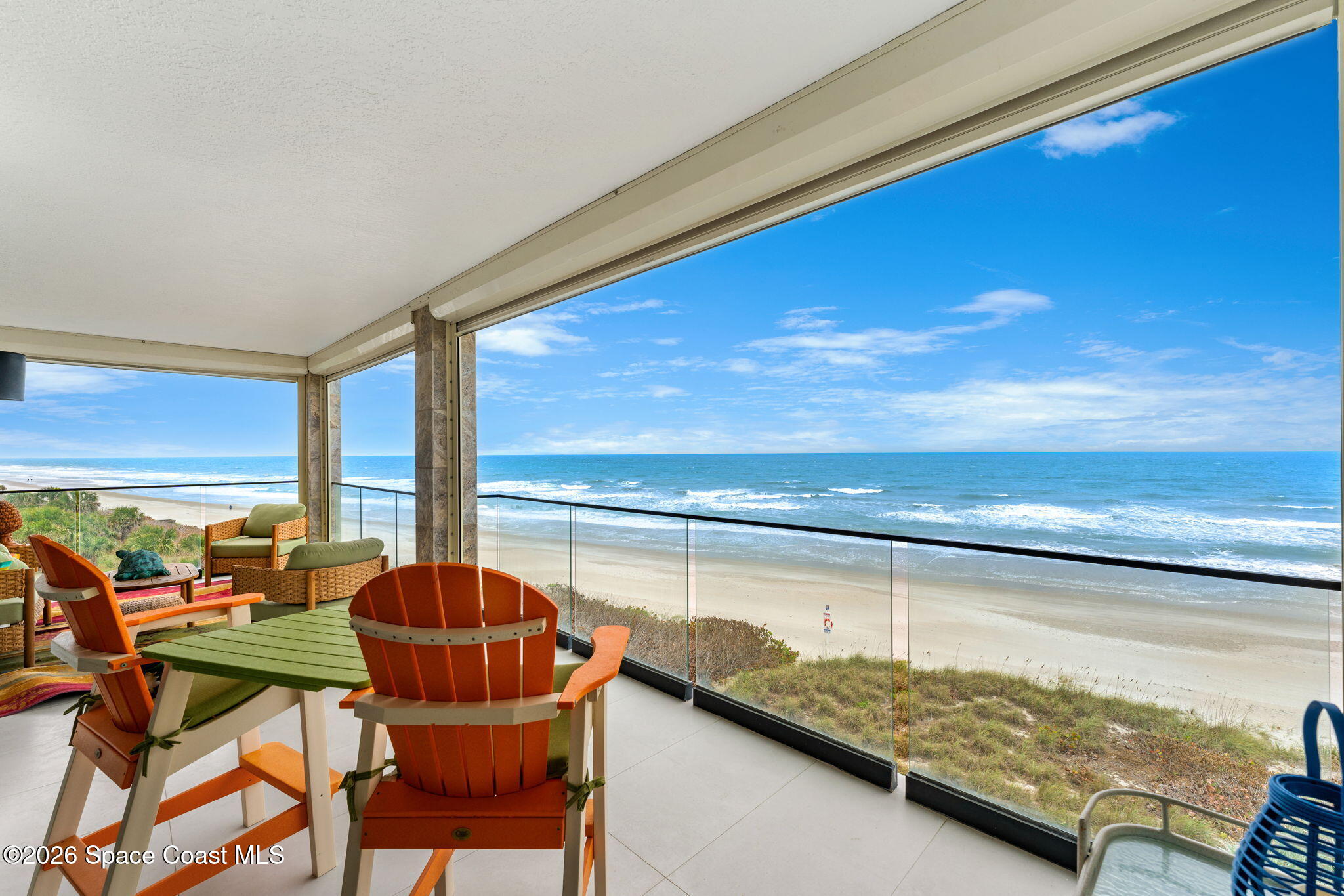 Covered oceanfront terrace at Residence 404 with lounge seating overlooking the wide beach and the Atlantic Ocean